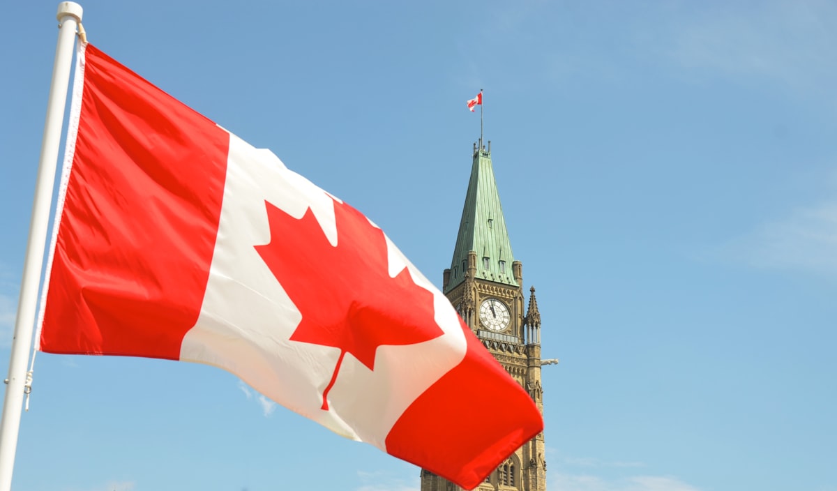 Canadian flag waving in front of Parliament Hill Peace Tower in Ottawa