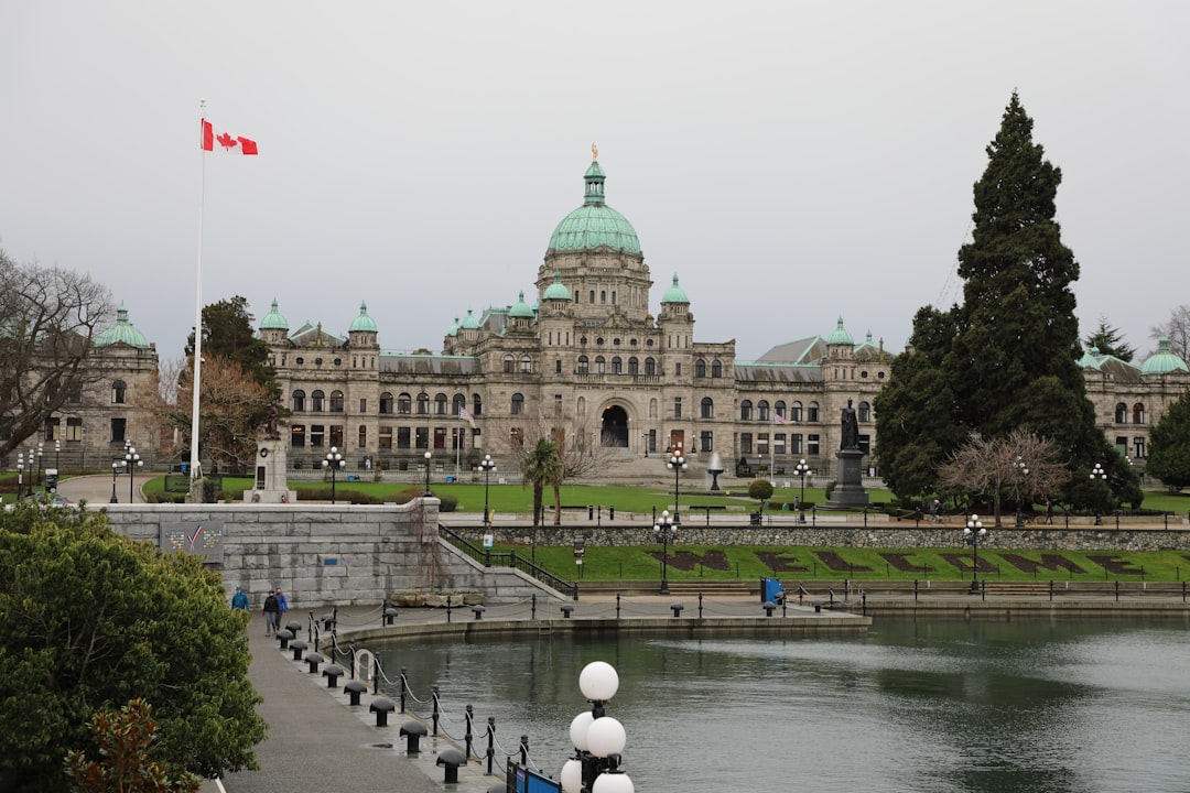 Canadian parliament building beside a reflective body of water with flag flying