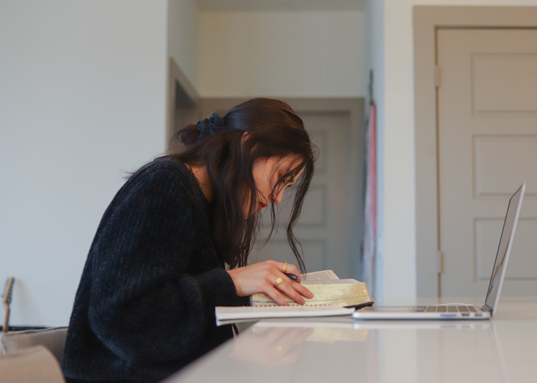 Young woman studying with laptop and books while preparing study permit extension documents