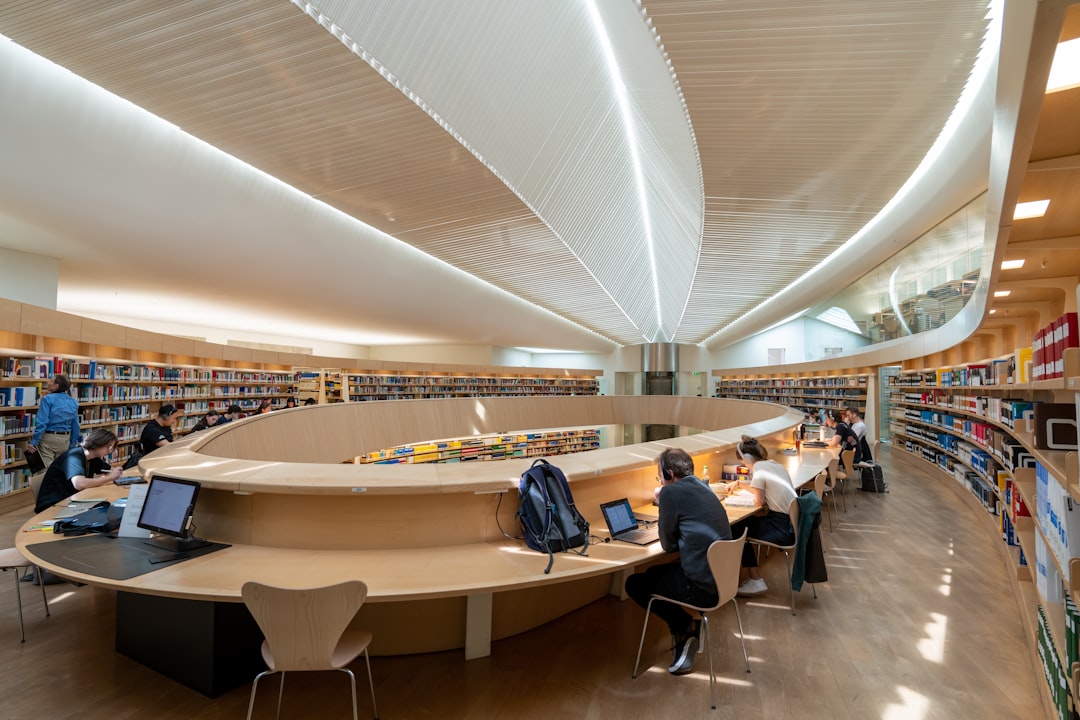 Students studying in a modern university library with bookshelves and curved desks for Canadian university admissions