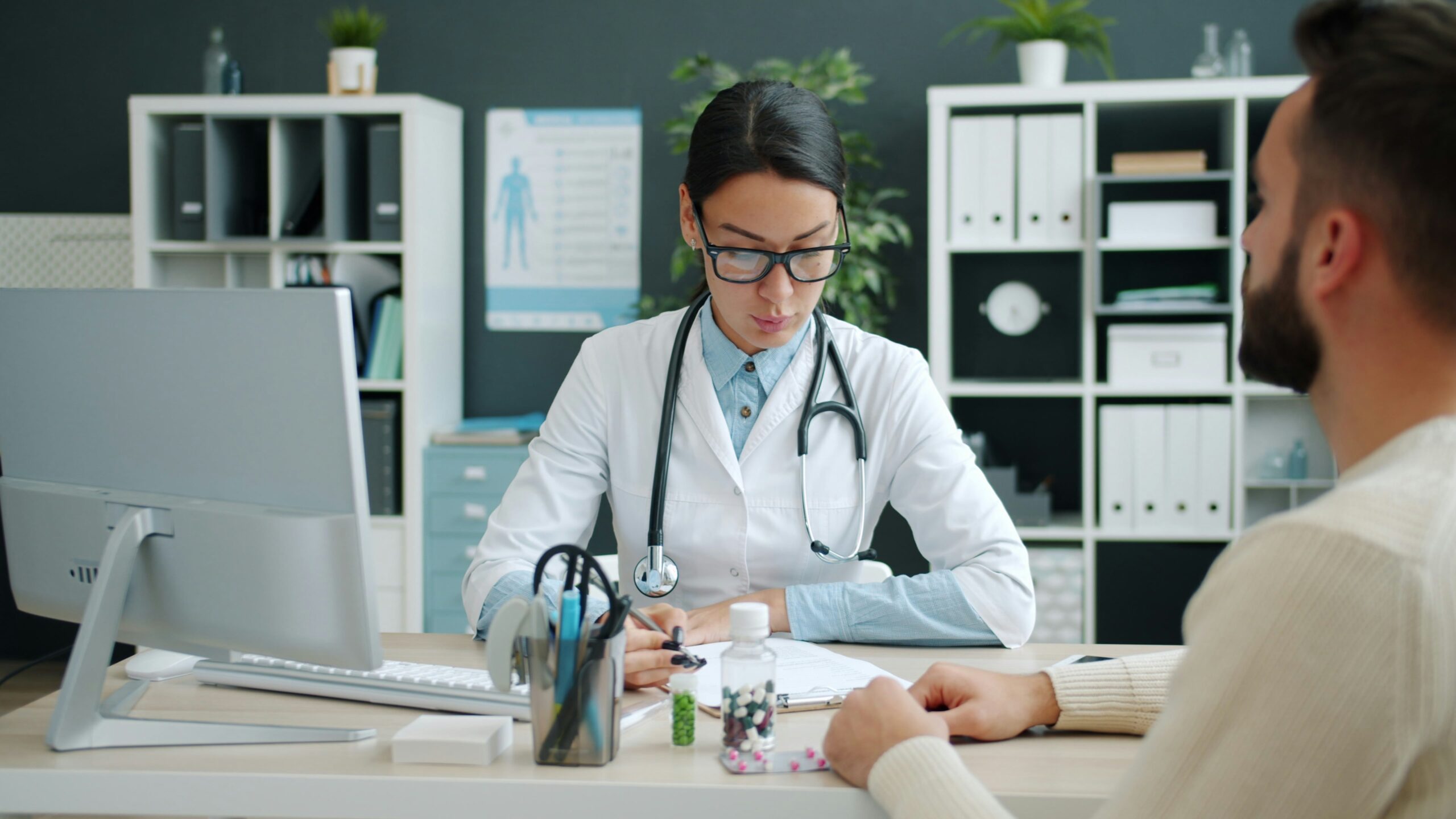 Doctor consulting with a young adult patient about student health insurance options at a medical office in Canada
