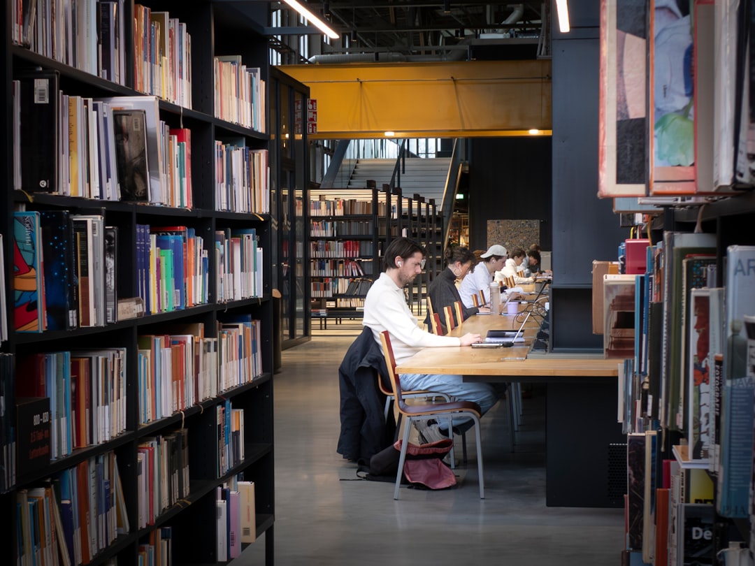 Students studying at wooden tables in a modern library with bookshelves for letter of acceptance preparation