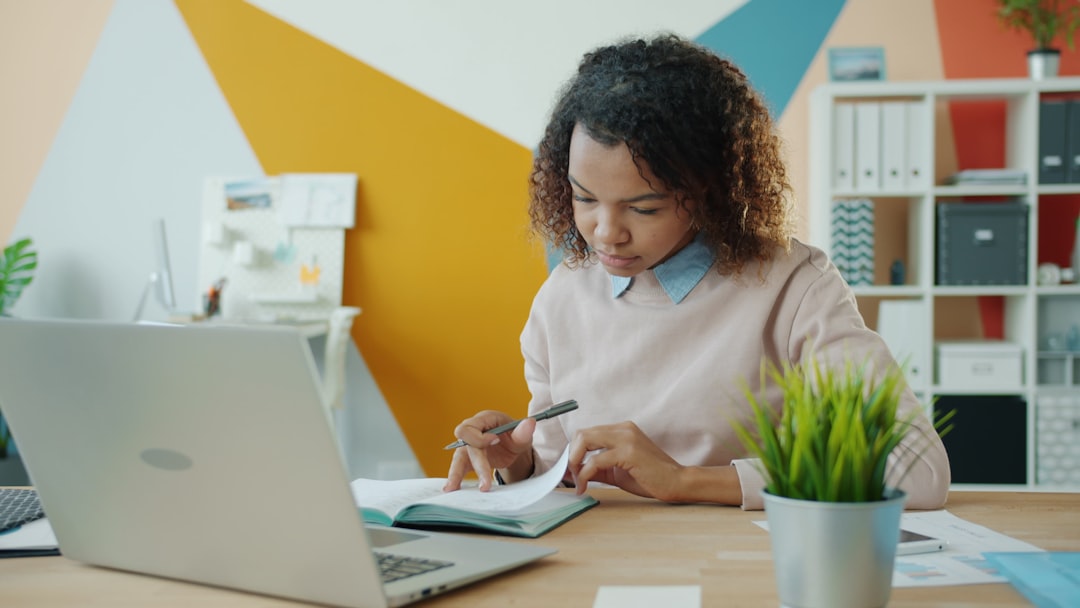 Young woman reviewing proof of funds documents at a desk with laptop and notebook