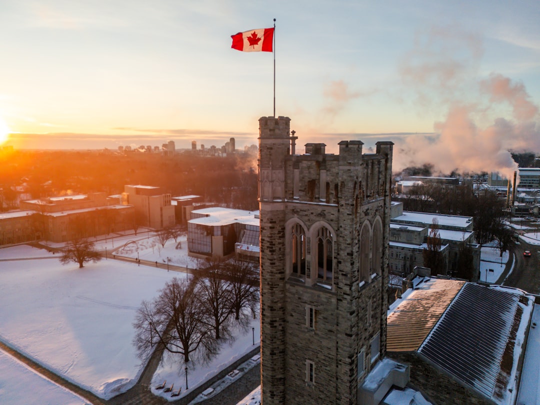Canadian flag flying atop a stone university tower at sunrise in winter
