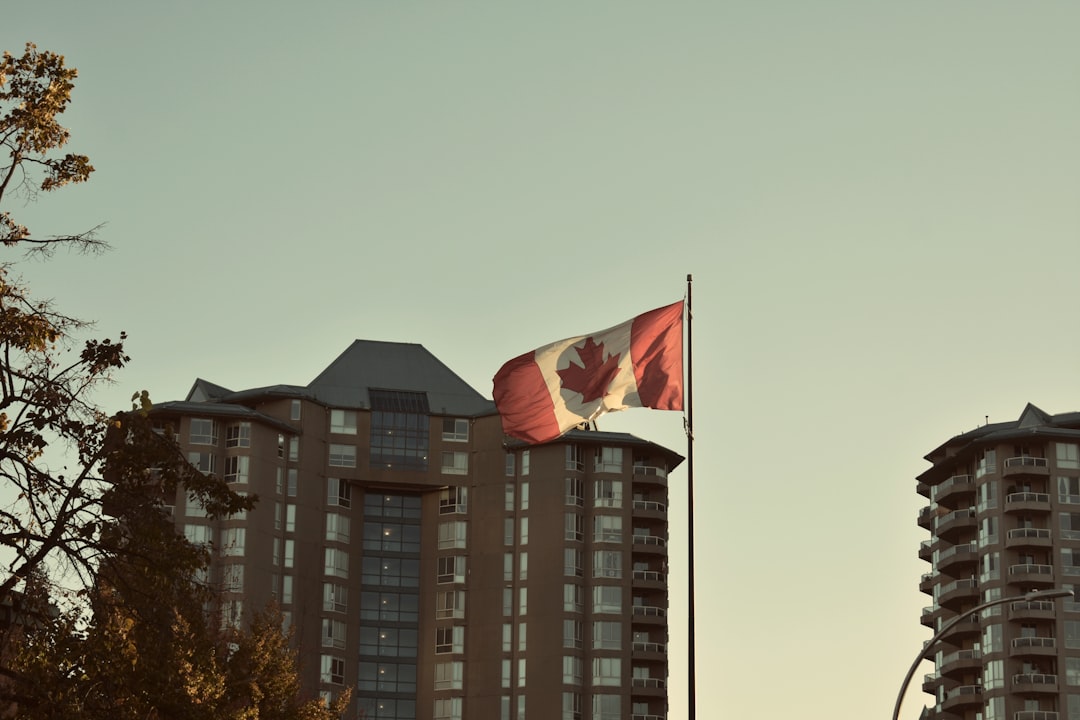 Canadian flag waving in front of residential apartment buildings at sunset