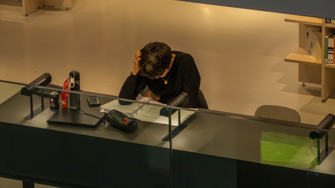 Stressed applicant reviewing study permit refusal documents at a desk