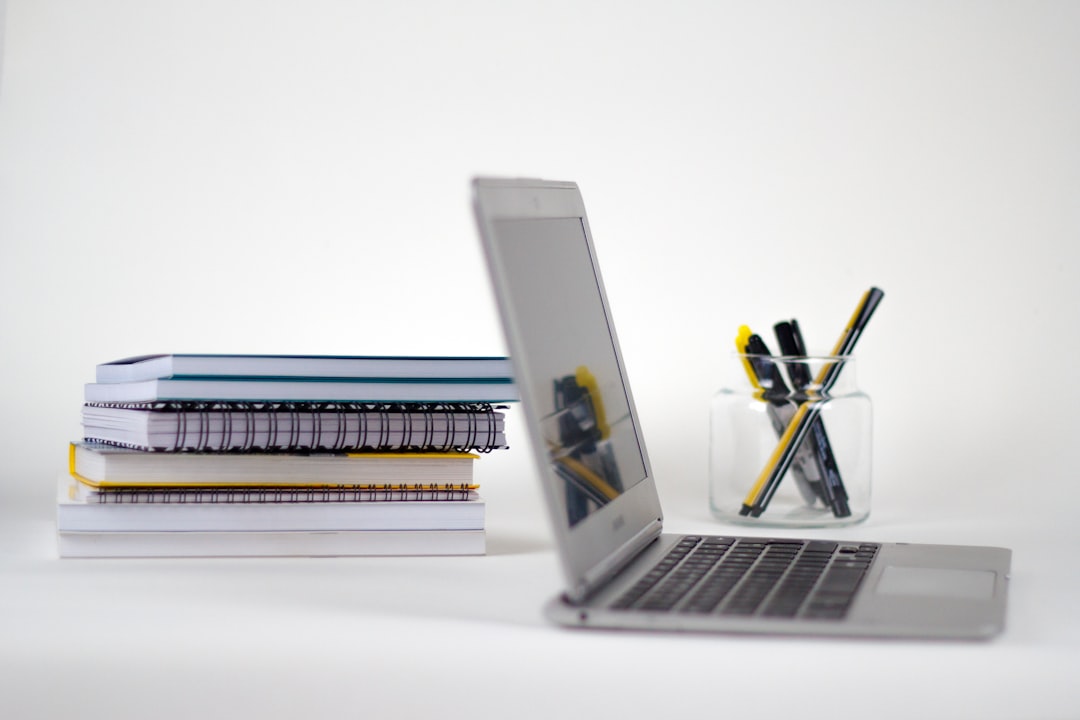 Laptop and stacked notebooks on a desk for TOEFL vs IELTS test preparation in Canada