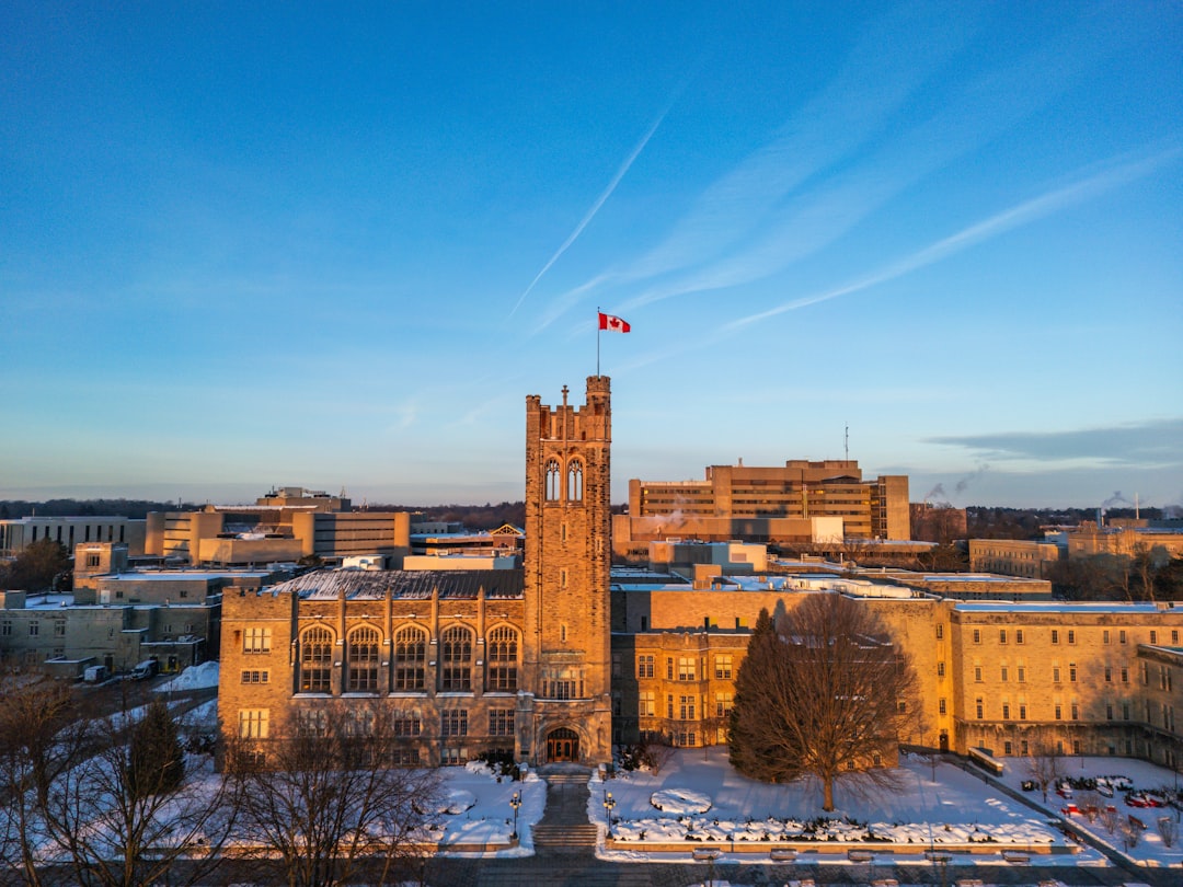 Canadian university campus building with stone architecture and Canadian flag under blue sky