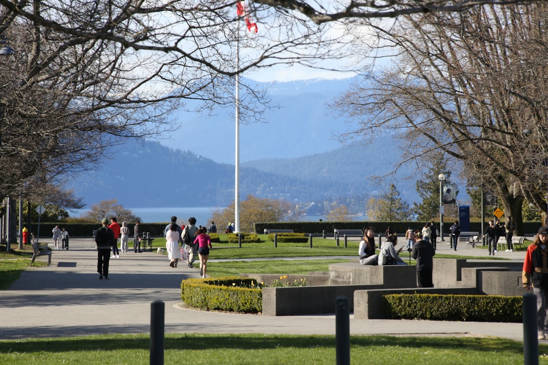 Students walking across UBC campus with mountains and Canadian flag in background