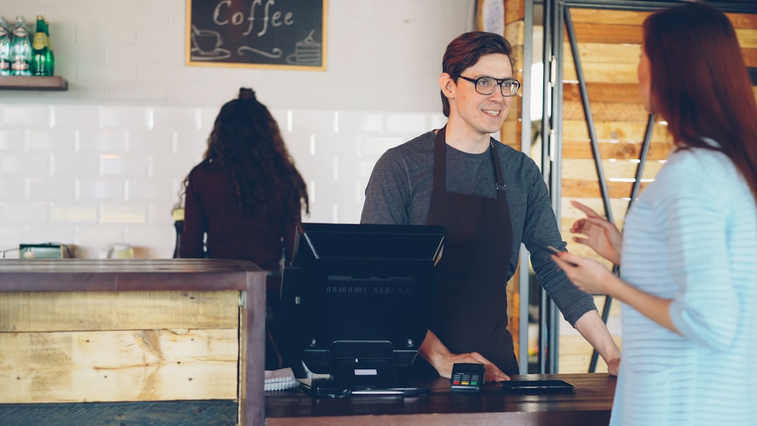 Young barista serving a customer at a coffee shop counter, a common part-time job for international students in Canada