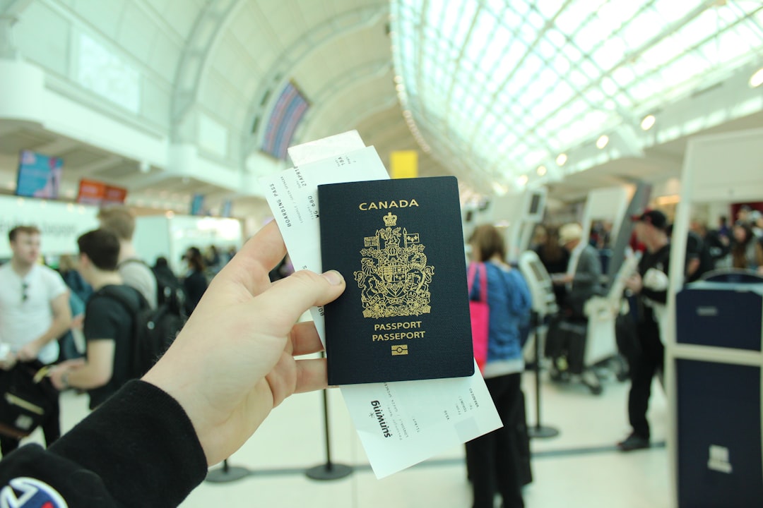 Person holding a Canadian passport with boarding pass at an airport terminal