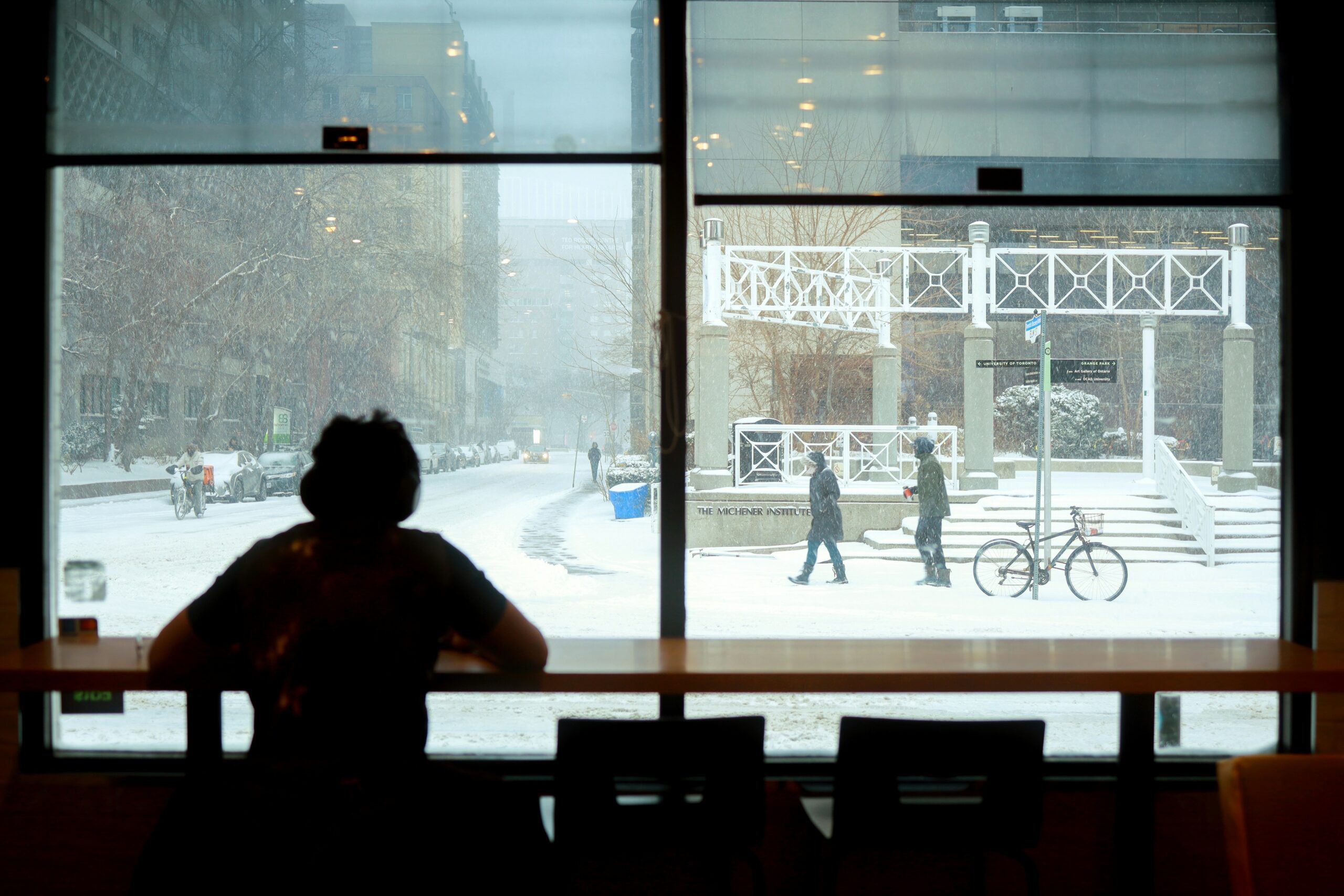 International student looking out at a snowy Toronto street during a Canadian winter
